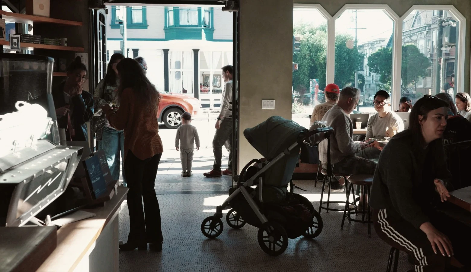 The room mid-morning: daylight through tall windows, people at tables along the counter