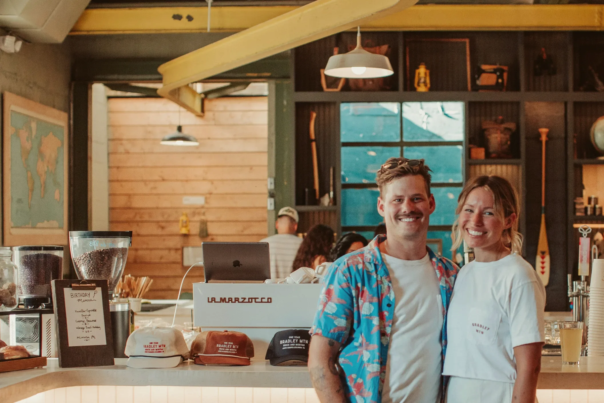 Two owners together behind the counter of their coffee shop.